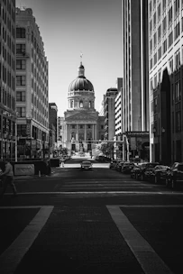 grayscale photo of cars parked on road near building