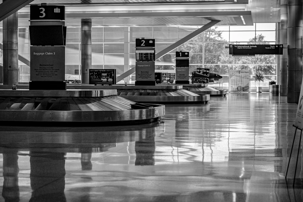 An empty airport departure gate with rows of seats and a jet bridge beyond