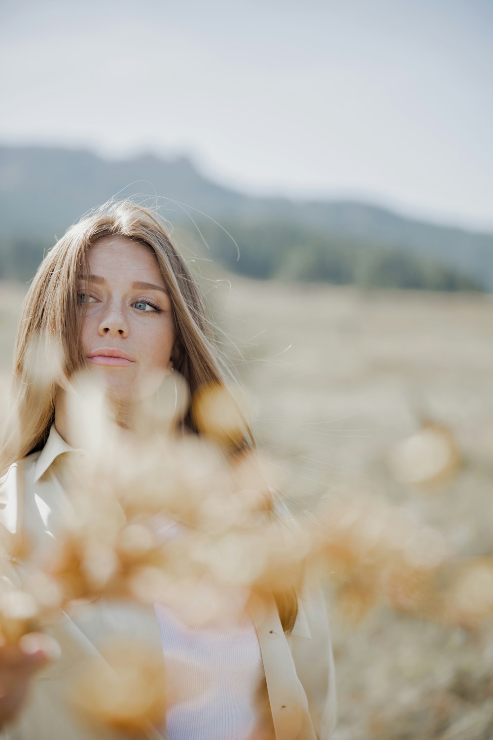 woman in white long sleeve shirt standing on brown grass field during daytime