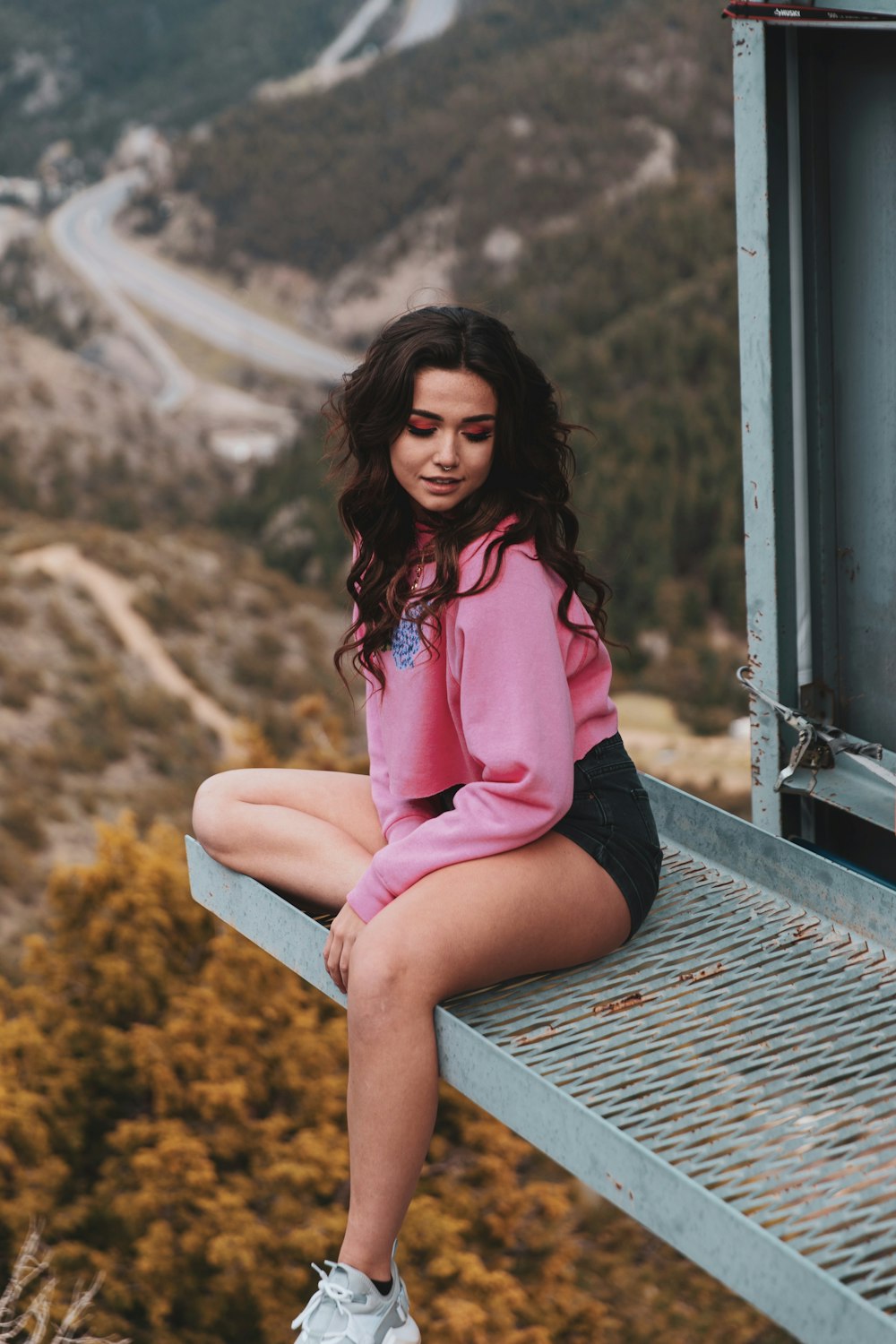woman in pink long sleeve shirt sitting on brown wooden bench