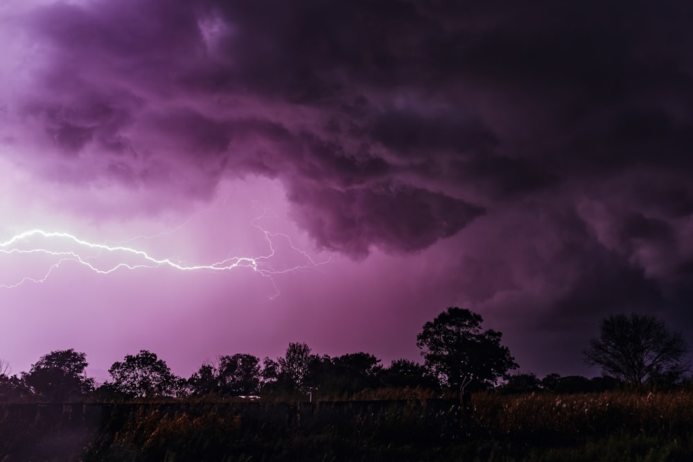 a purple storm is coming over a field