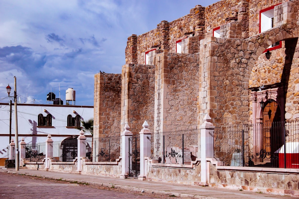 a stone building with red shutters and a gate