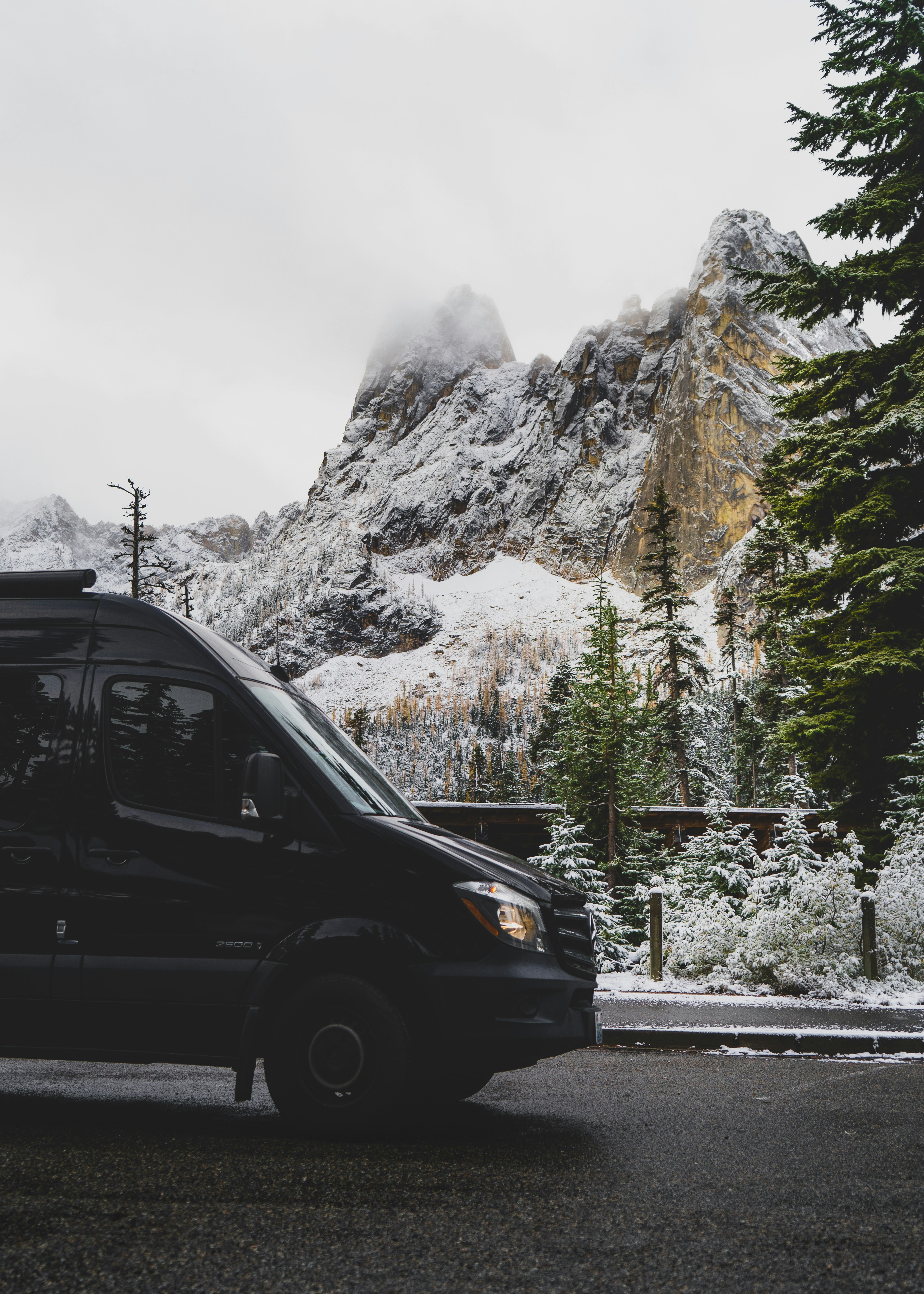 낮에는 눈 덮인 산 근처 도로에서 검은 색 SUV