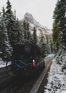 Shuttle truck loaded with bikes climbing the steep hillside surrounded by dense forest.