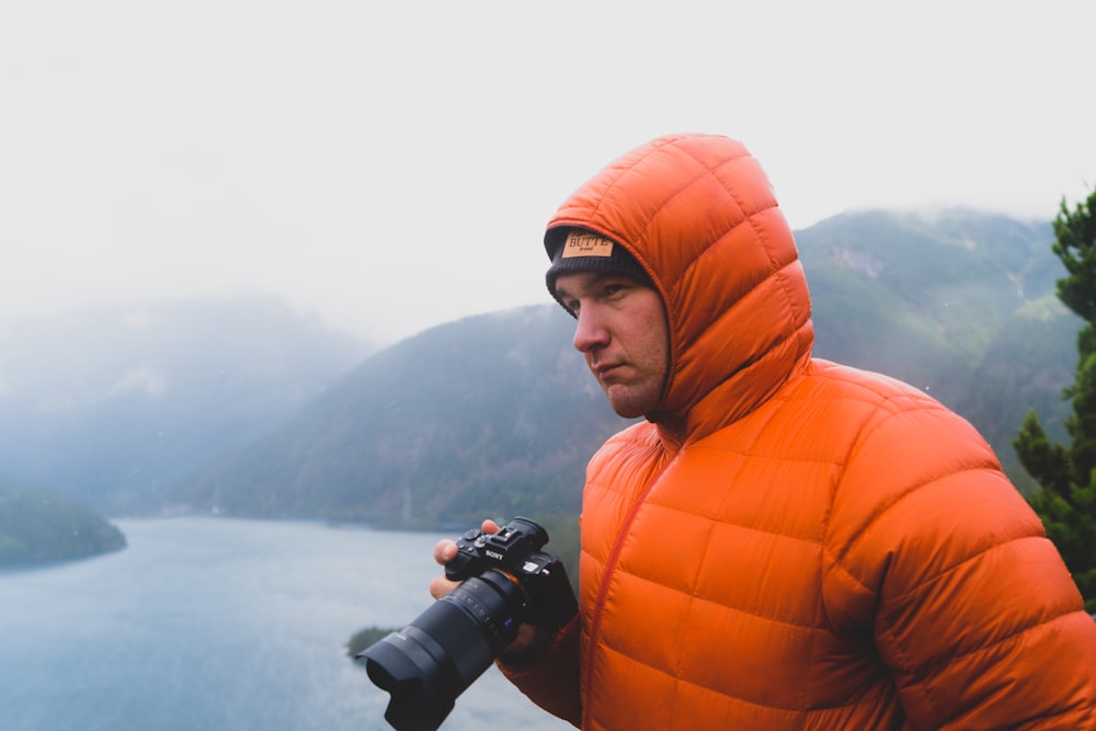 woman in orange bubble jacket holding dslr camera