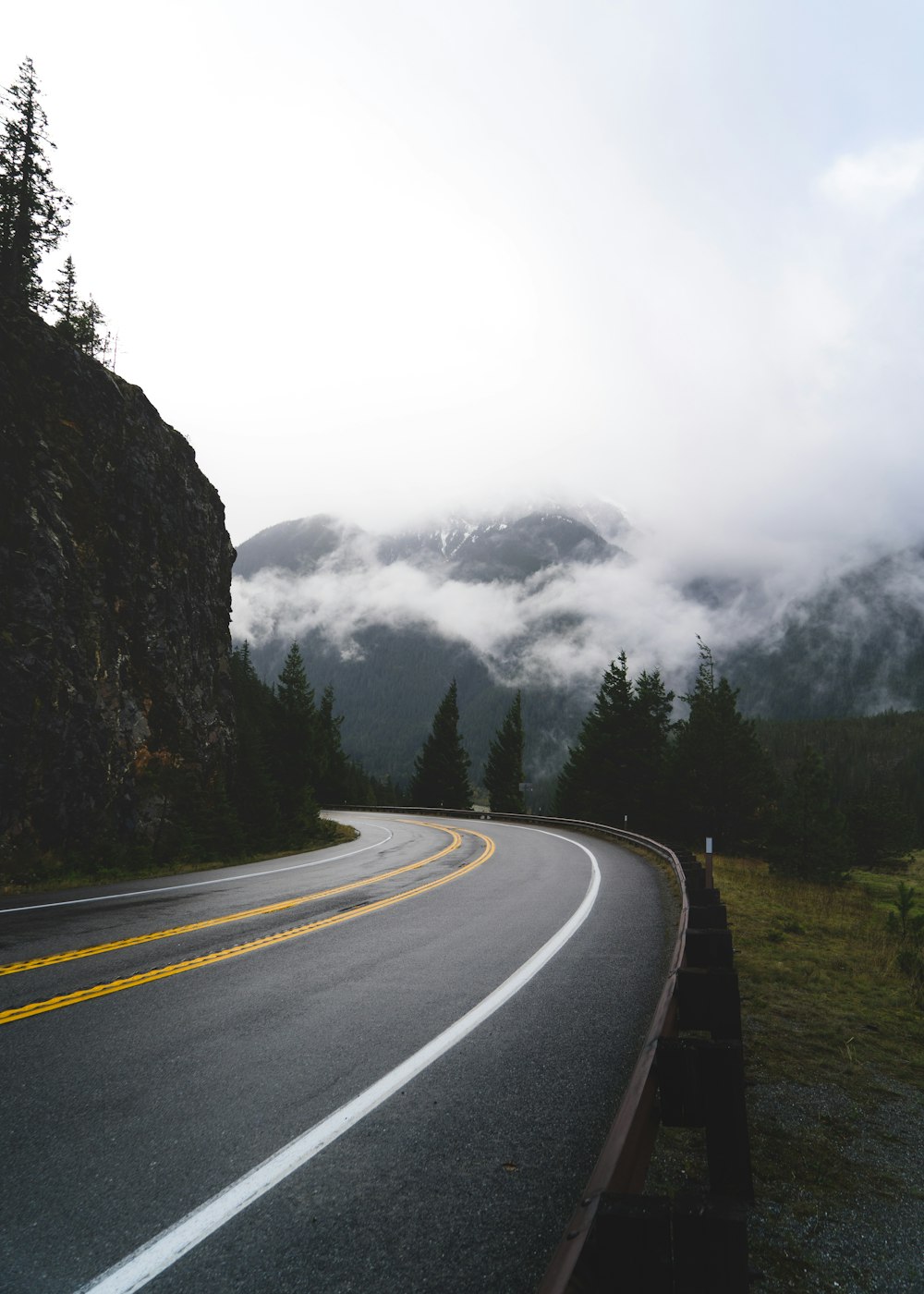 gray concrete road between green grass field and mountain during daytime