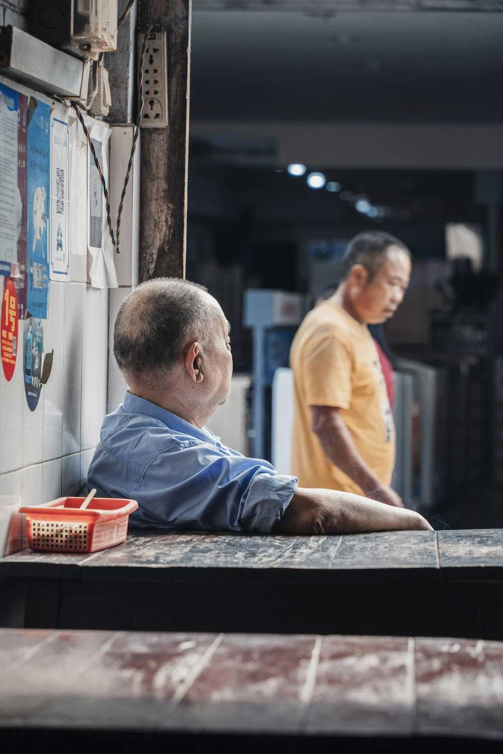 man in yellow crew neck t-shirt sitting on brown wooden bench during daytime