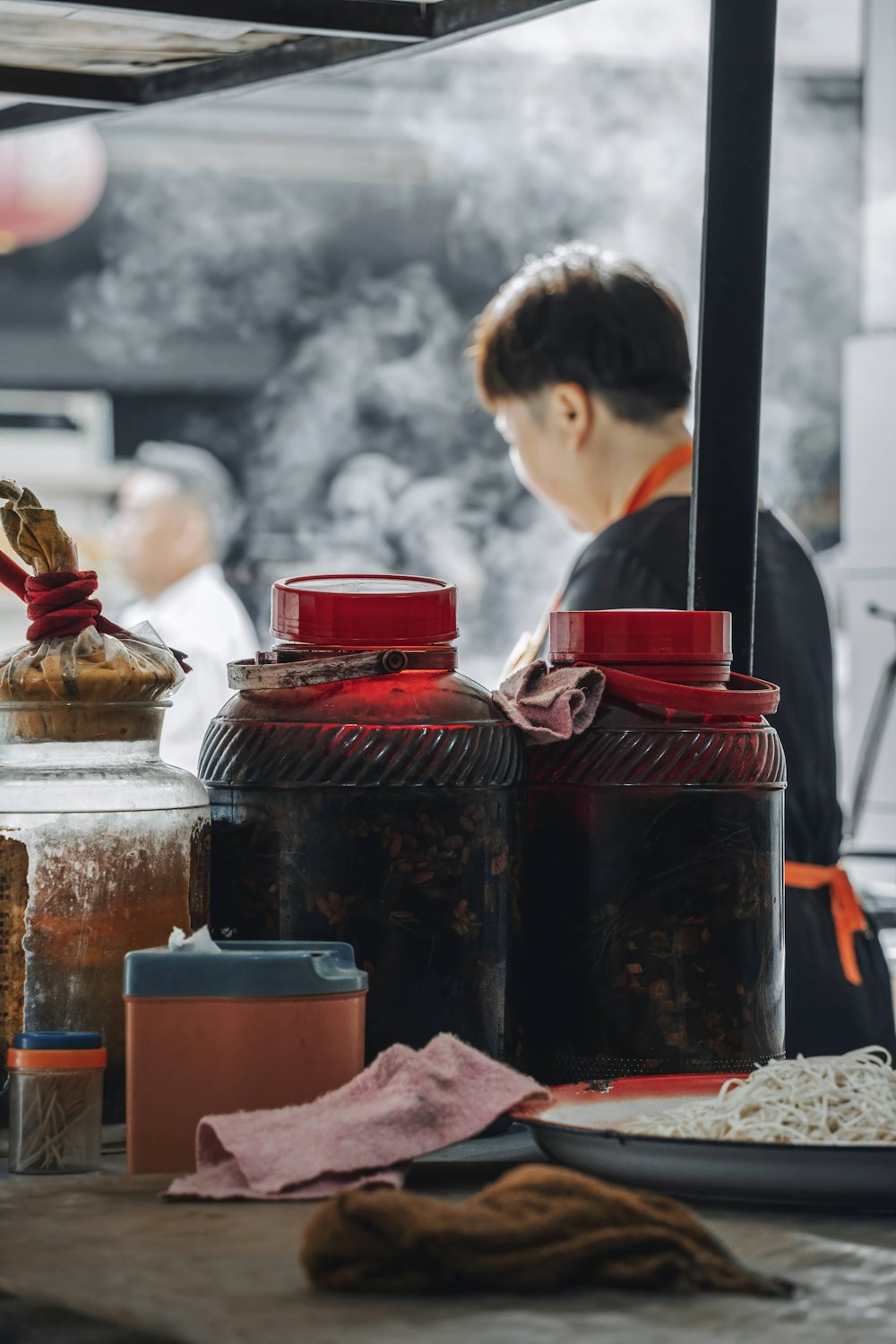 woman in black long sleeve shirt standing in front of brown wooden table with jars