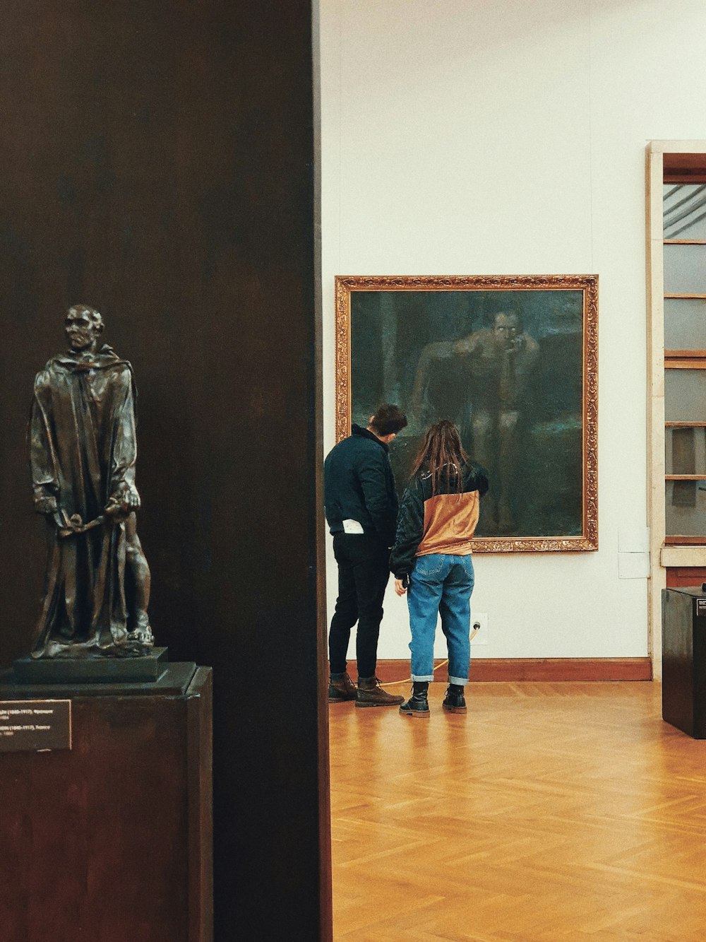 man in blue long sleeve shirt standing beside statue