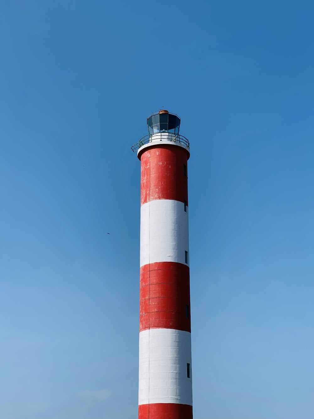 red and white concrete lighthouse under blue sky during daytime