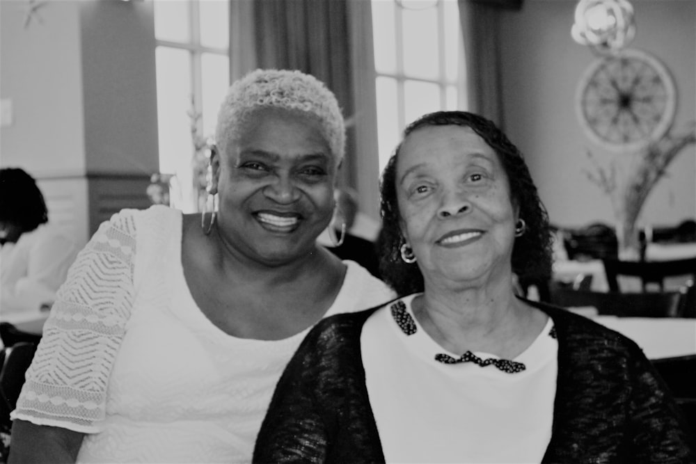 woman in black and white shirt smiling beside woman in white crew neck shirt