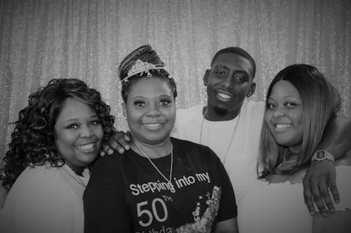 A candid photo of the birthday woman surrounded by smiling friends and family, all sharing a joyful moment.