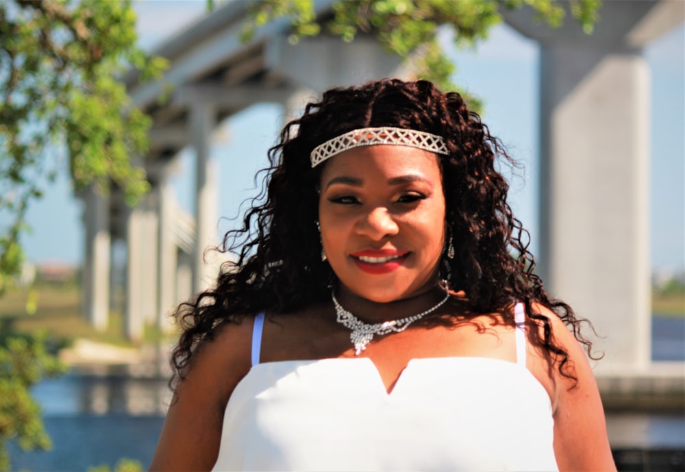 woman in white sleeveless top wearing black and white floral crown