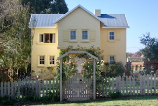 beige concrete house with white wooden fence