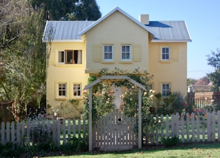 beige concrete house with white wooden fence