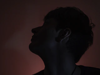 Artistic photo of a piercing on an ear with dark, moody lighting.