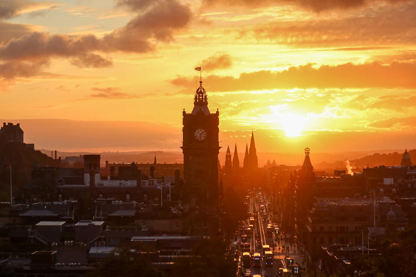 Sun setting behind the Balmoral clock tower and Princes Street in Edinburgh, a popular next stop after London