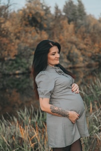 Pregnant woman gently holding her belly in a peaceful natural setting.