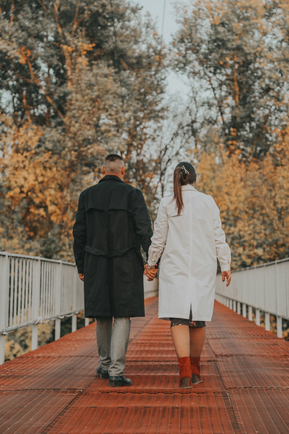 man and woman standing on brown wooden bridge during daytime