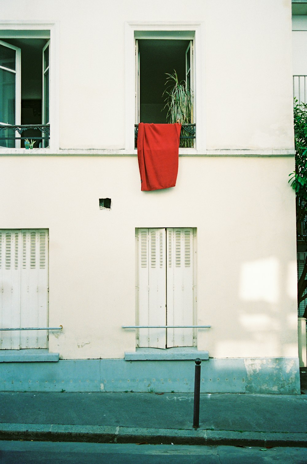 a white building with a red cloth hanging out of the window