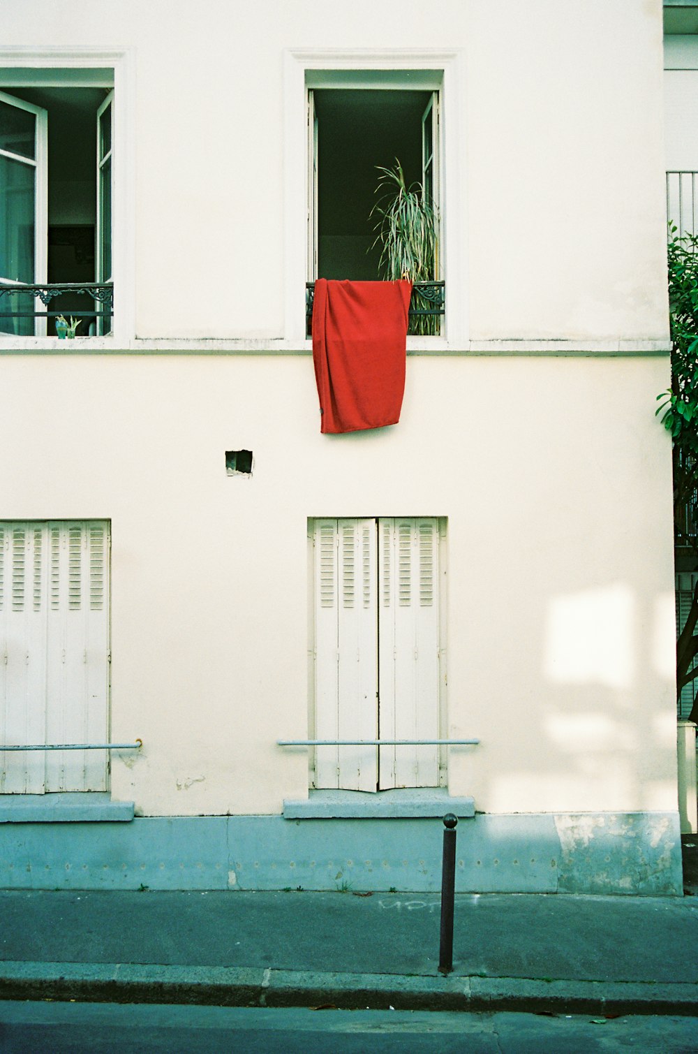 um edifício branco com um pano vermelho pendurado para fora da janela