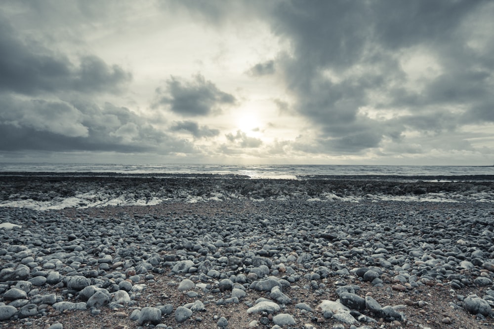 gray and black stones on seashore under gray clouds
