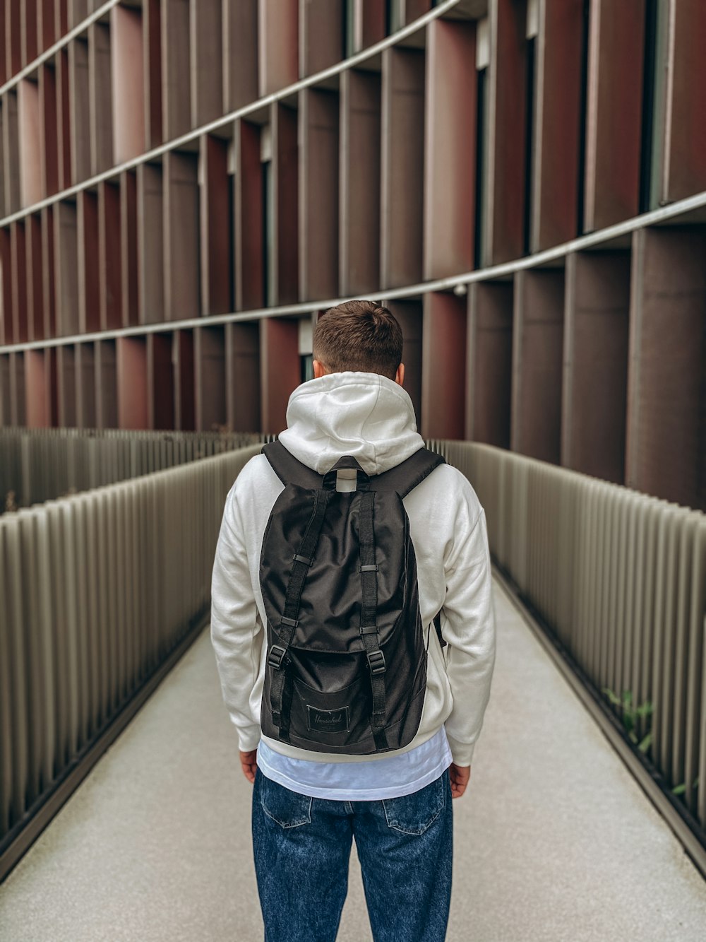 man in white jacket and blue denim jeans walking on bridge