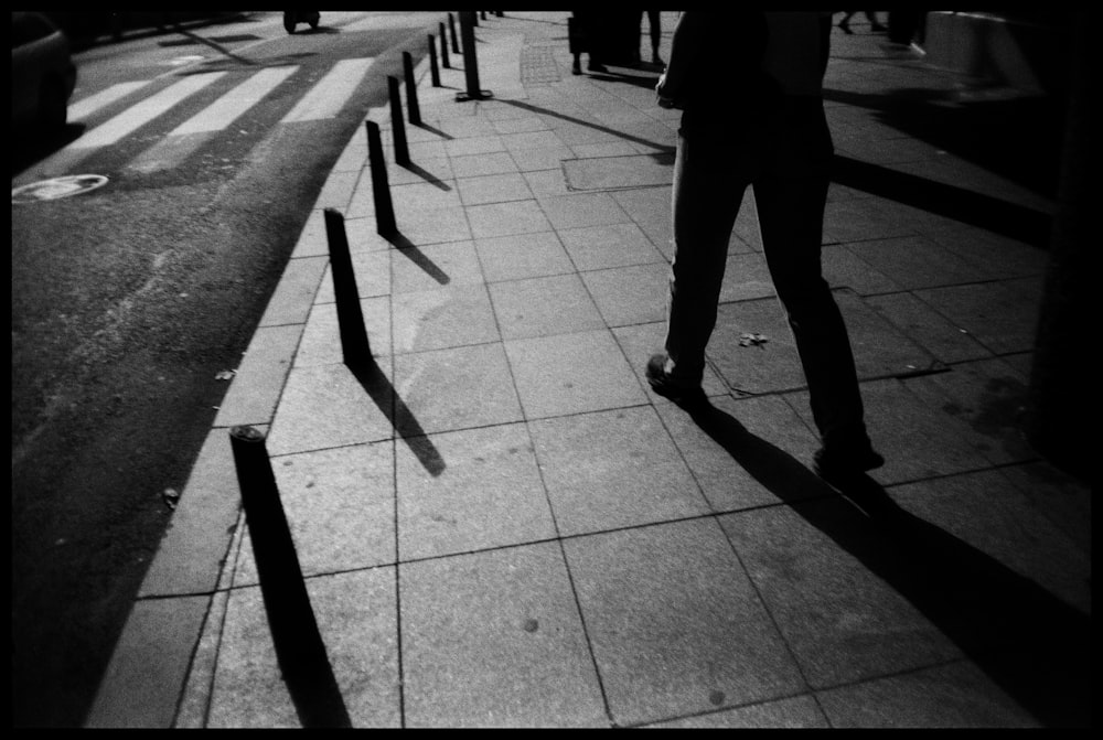 man in black pants walking on sidewalk during daytime