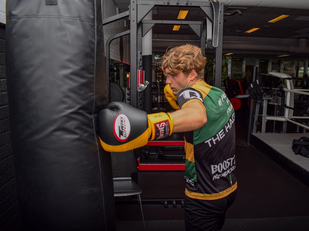 boy in green t-shirt and black shorts carrying black and red boxing gloves