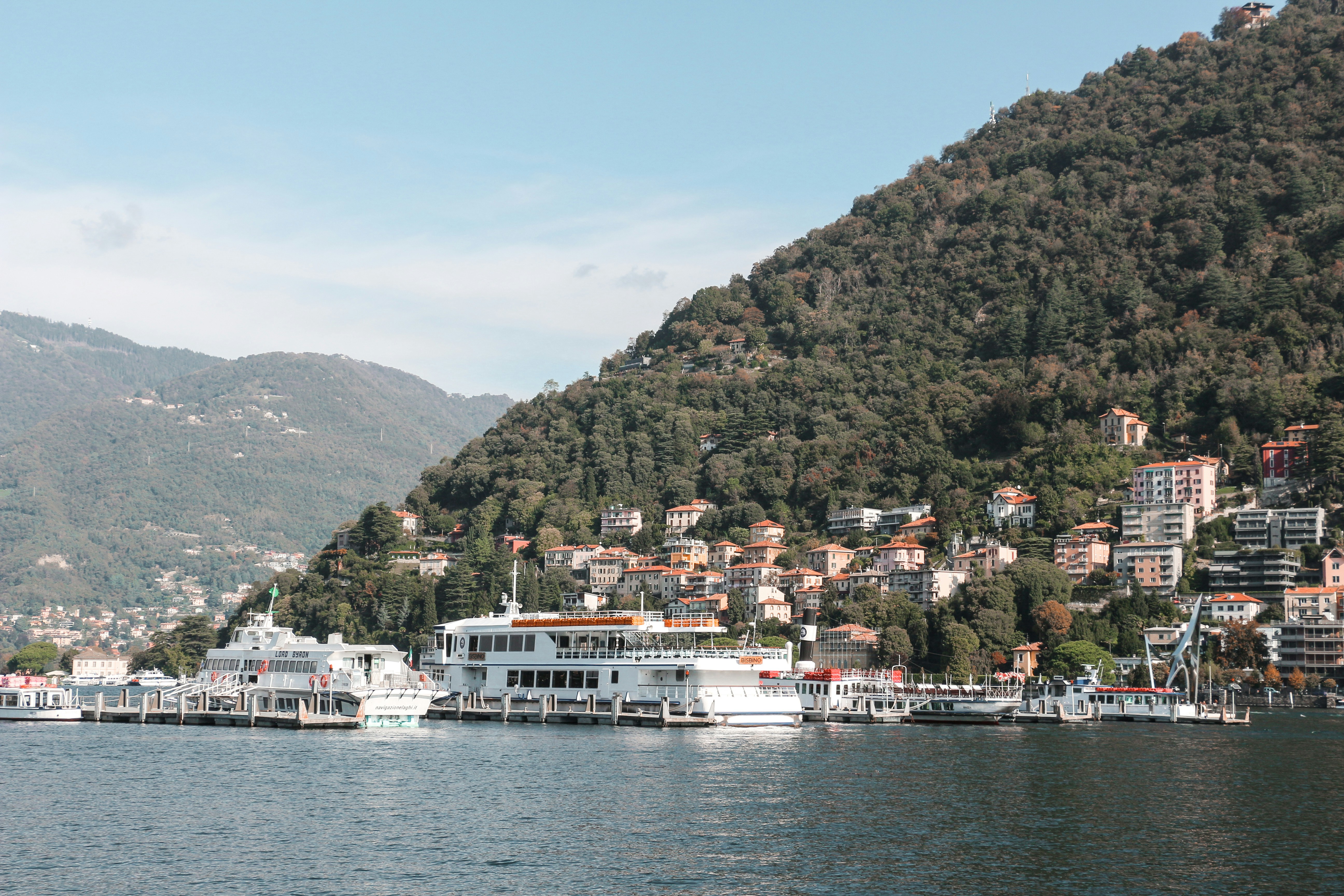white boat on body of water near green mountain during daytime