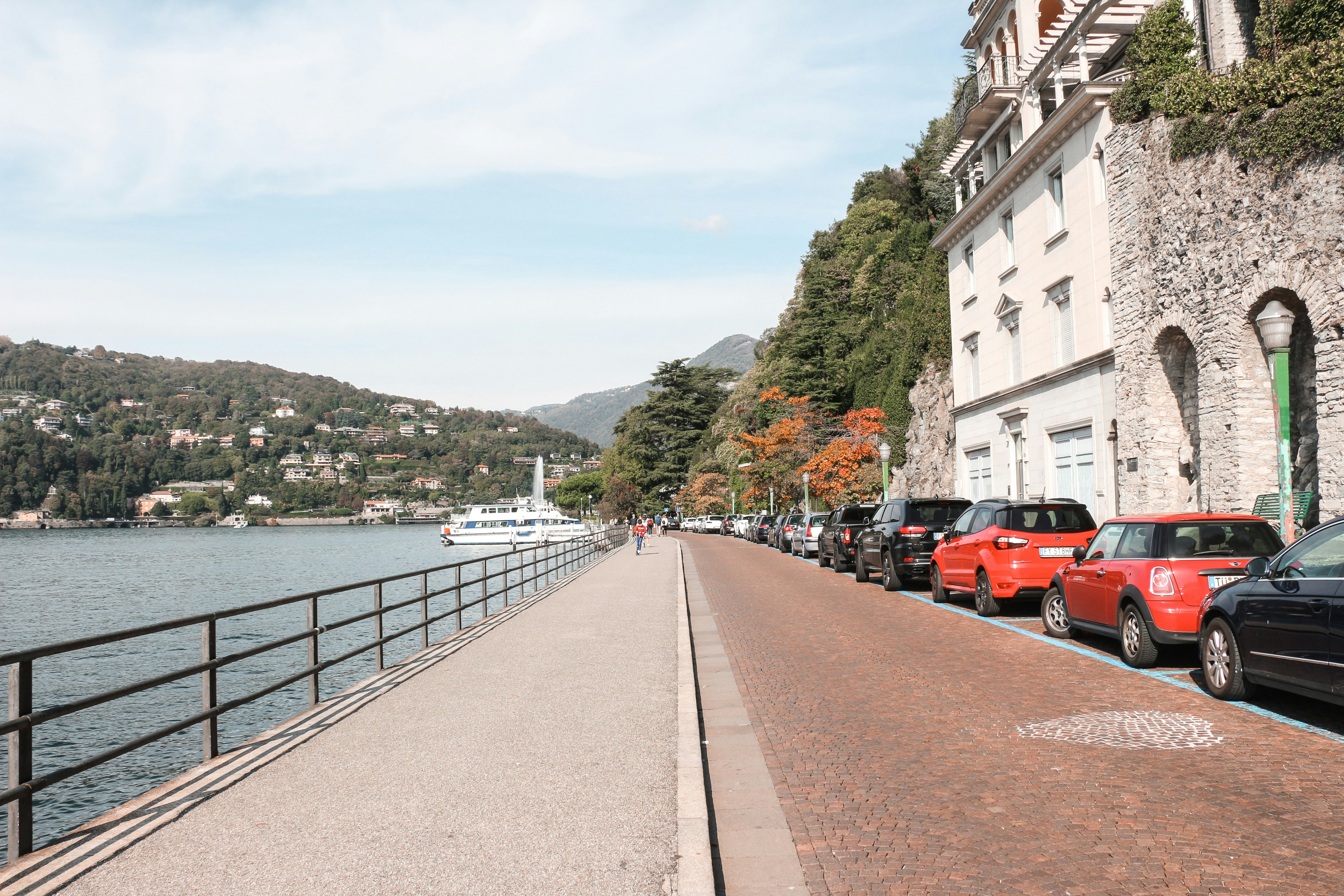 red car parked beside the road near the river during daytime
