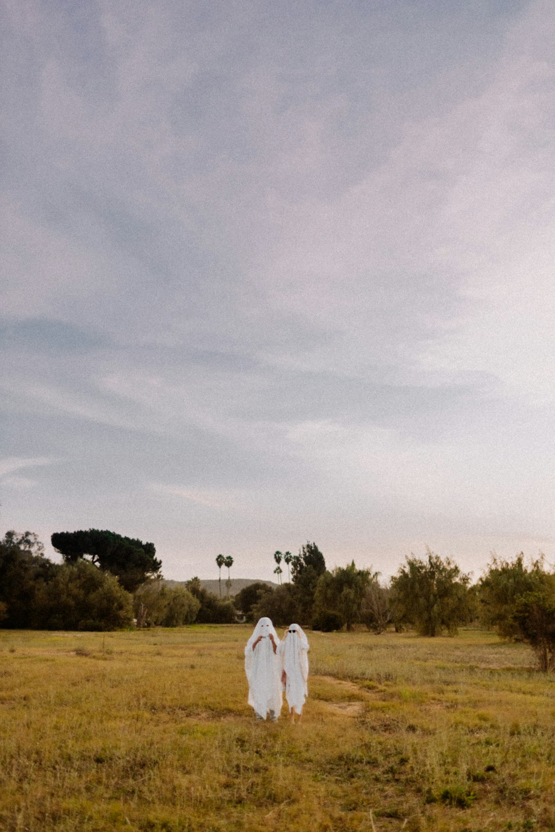 person in white long sleeve shirt standing on green grass field under white cloudy sky during