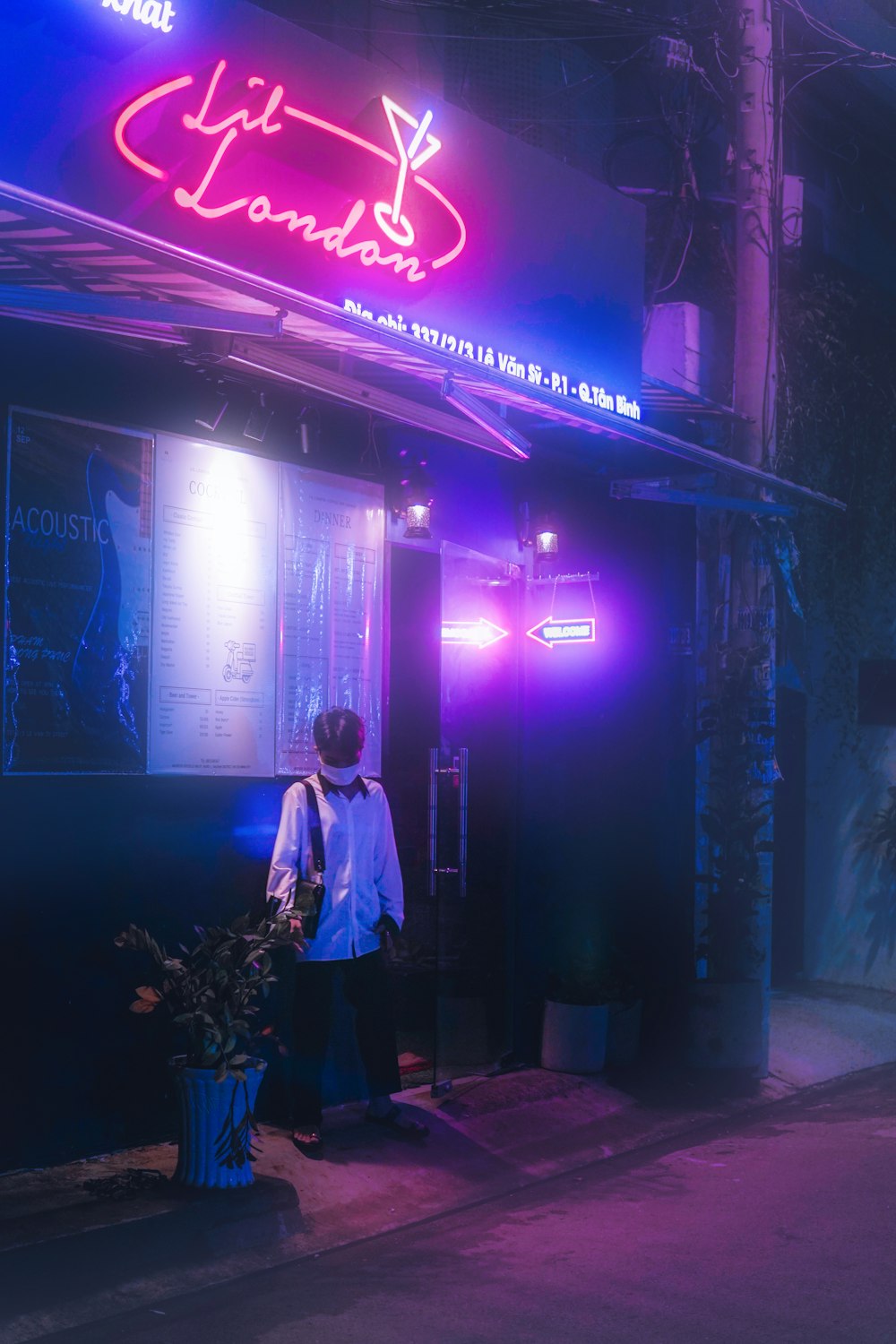 man in white dress shirt standing near purple neon signage