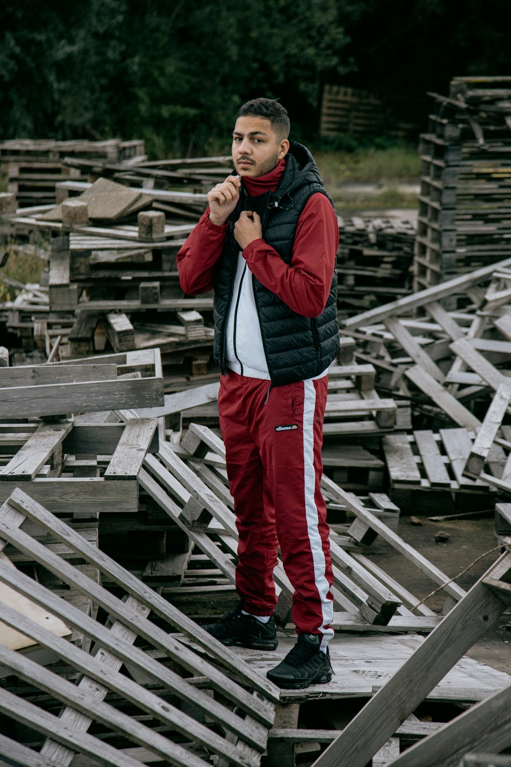 man in black jacket and red pants standing on wooden stairs