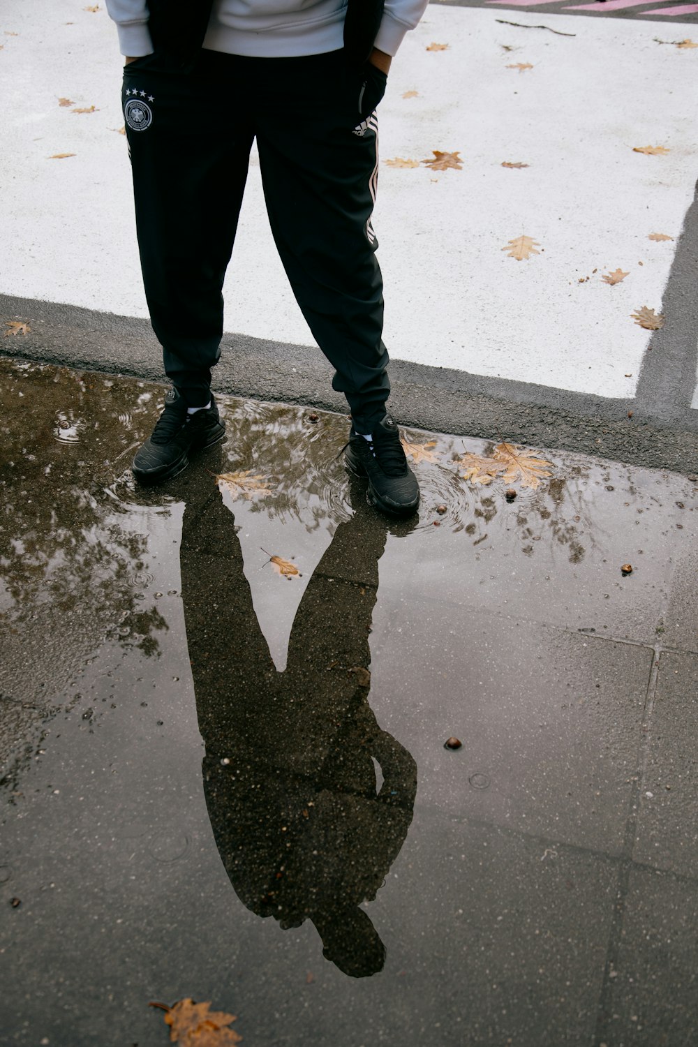 Persona in pantaloni neri e stivali neri in piedi sul pavimento di cemento grigio