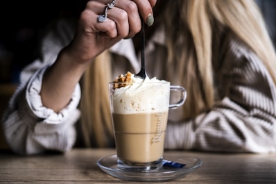 person holding clear glass mug with brown liquid