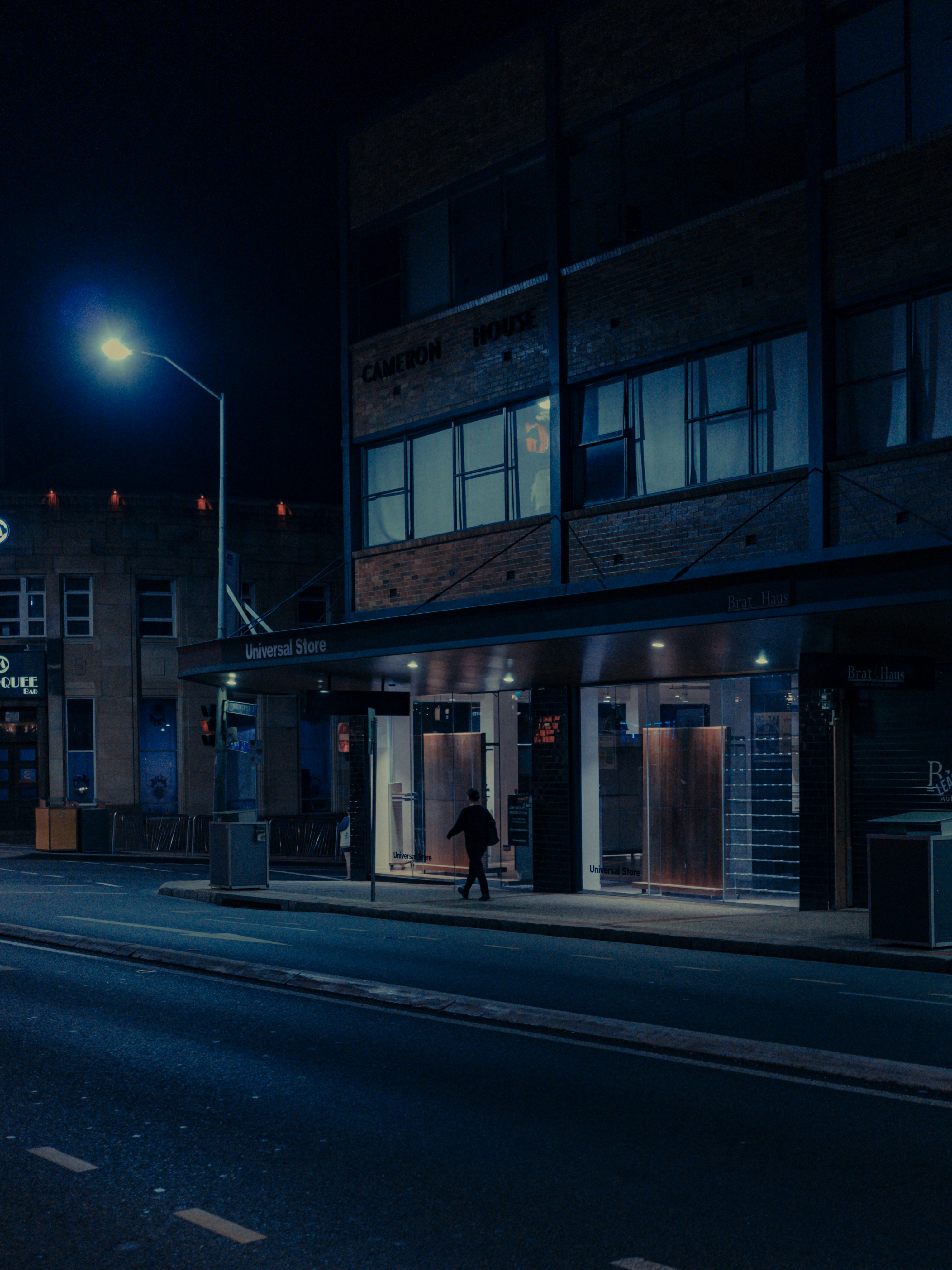 man in black jacket standing in front of store during night time