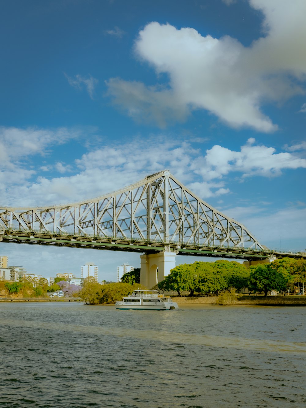 ponte de metal branco sobre o rio sob o céu azul durante o dia