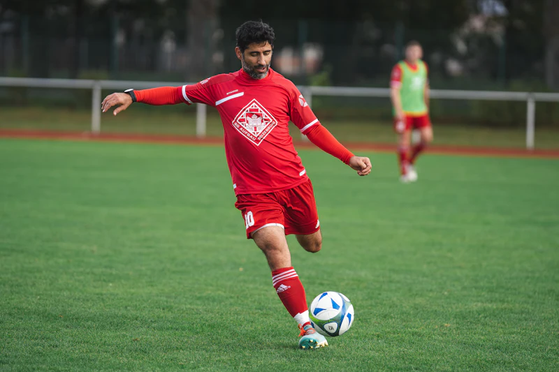 Joueur en maillot rouge frappant un ballon