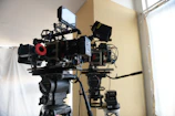 Film crew setting up vintage cameras under warm white lighting in an elegant corner.