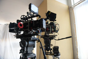 Film crew setting up vintage cameras under warm white lighting in an elegant corner.