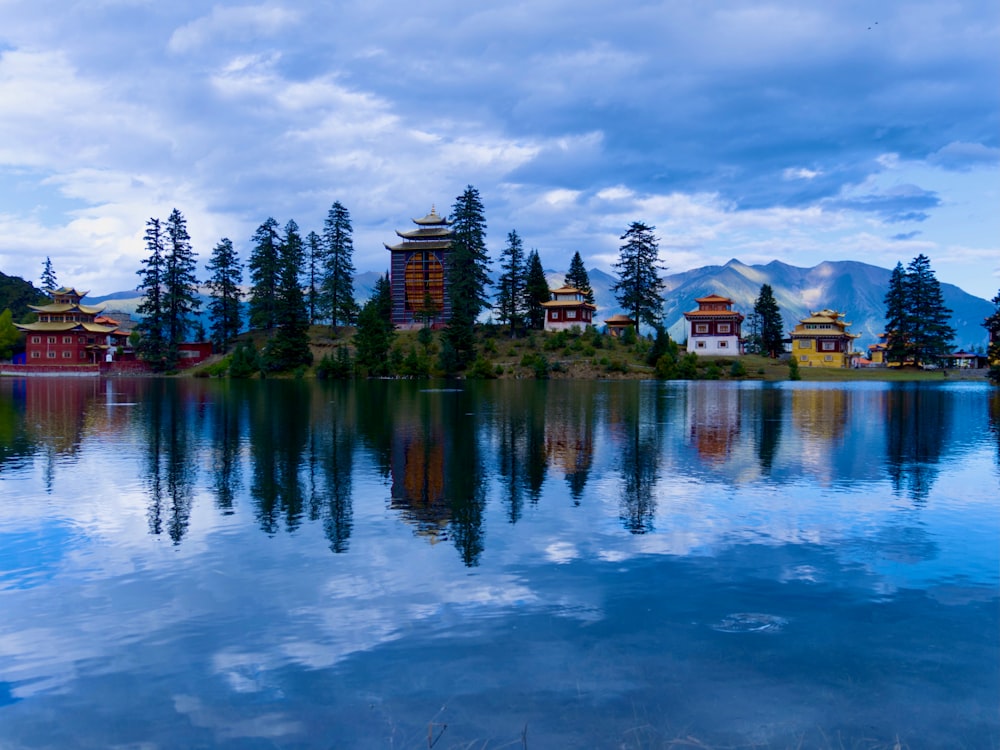 body of water near green trees under cloudy sky during daytime