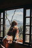 woman in red and white floral long sleeve shirt sitting on brown wooden chair