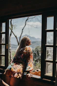 woman in red and white floral long sleeve shirt sitting on brown wooden chair
