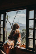 woman in red and white floral long sleeve shirt sitting on brown wooden chair