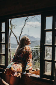 woman in red and white floral long sleeve shirt sitting on brown wooden chair
