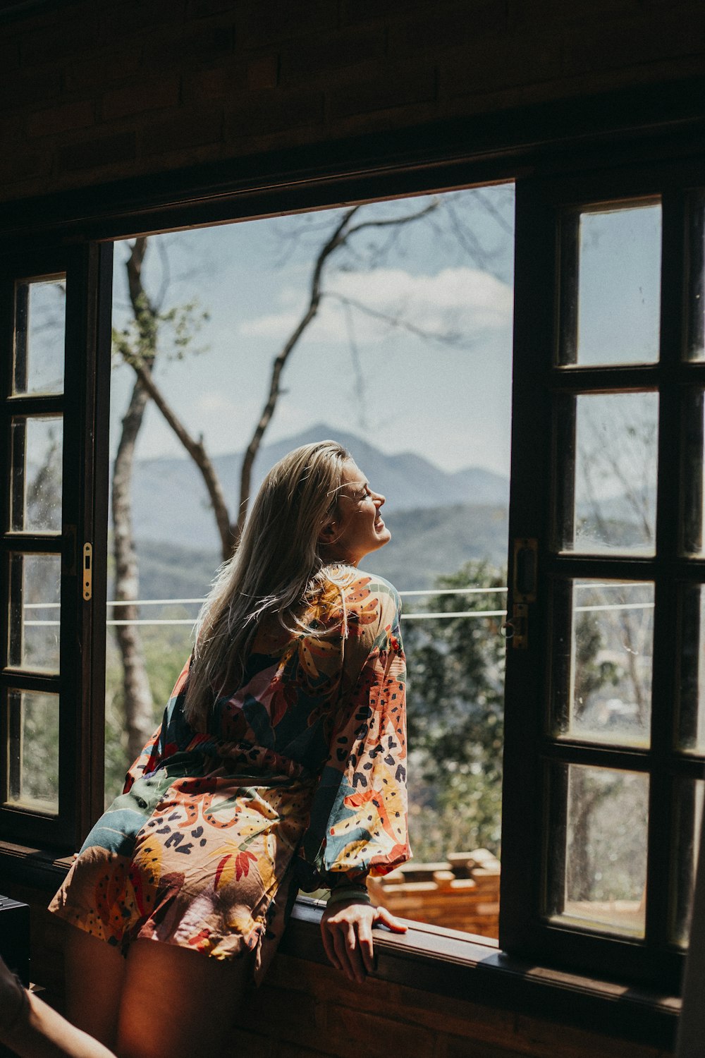 woman in red and white floral long sleeve shirt sitting on brown wooden chair