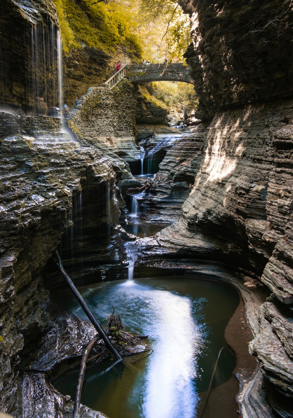 water falls between brown rocky mountain during daytime