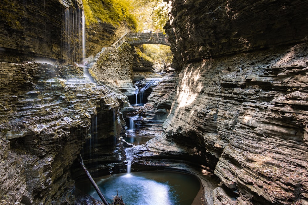 water falls between brown rock formation during daytime