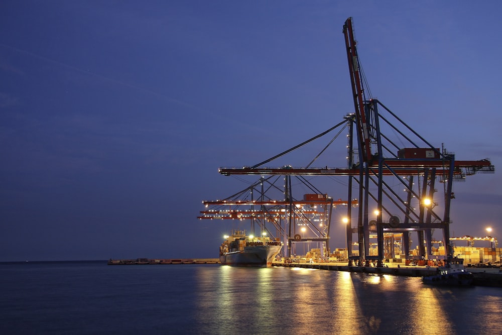 silhouette of crane near body of water during night time